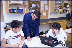 Secretary of Education Atif Qarni watches students work 